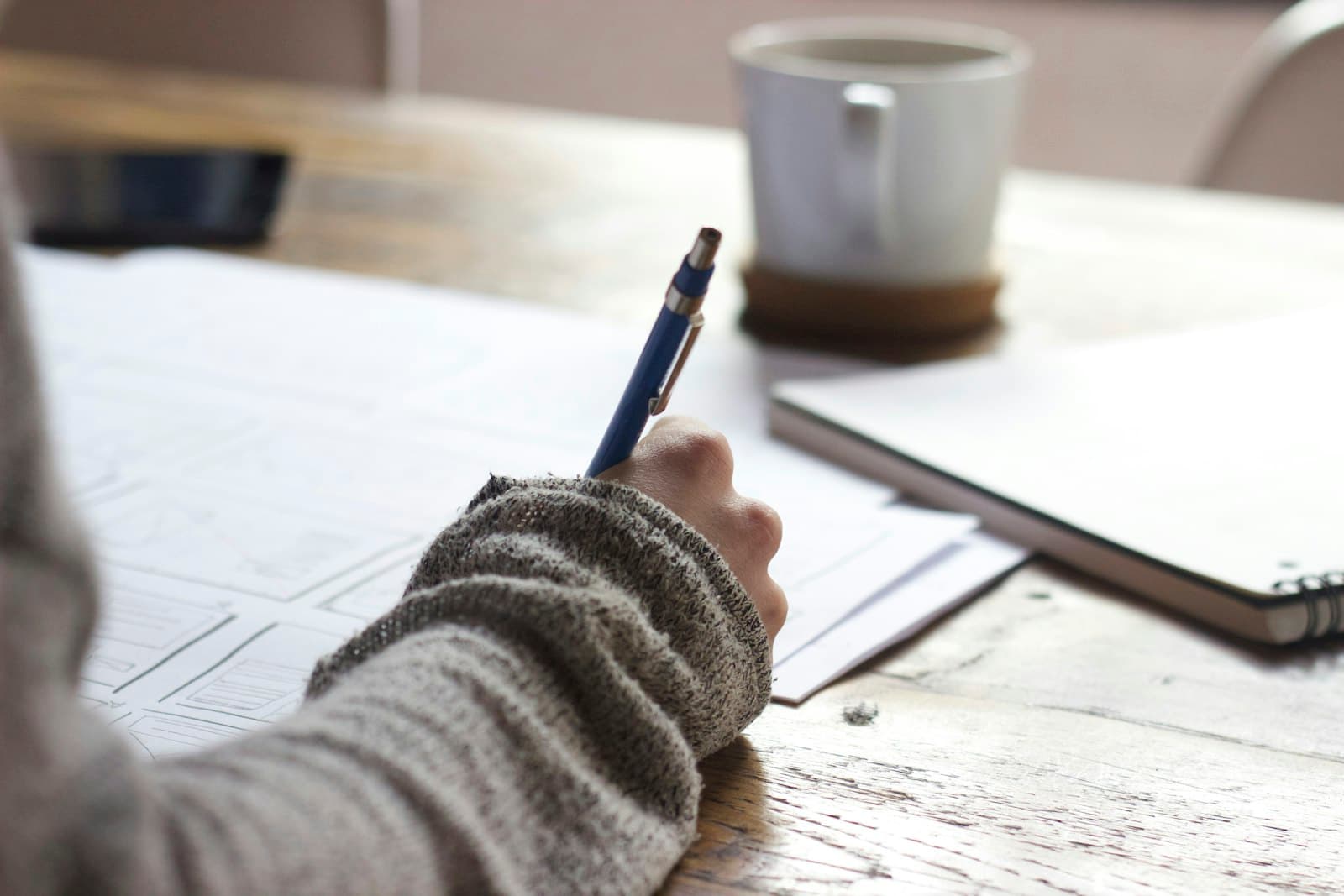 A student writing application notes at a desk